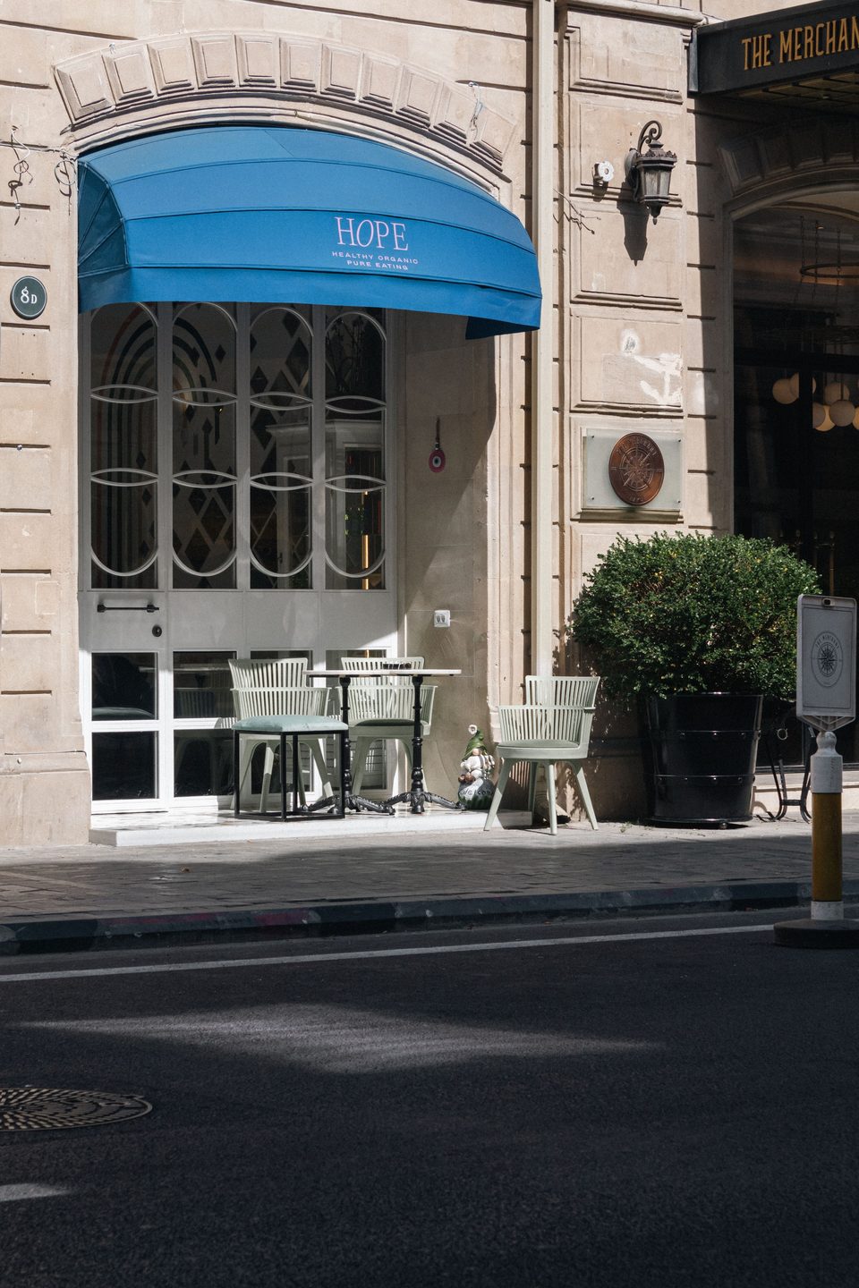Street cafe tables under a blue awning. Style example, not an Arc Signage Co project.