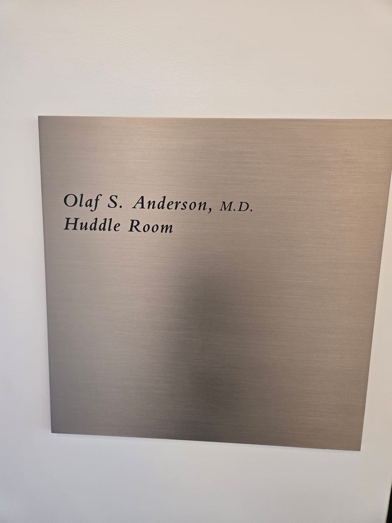 Brushed metal room ID plaque with tactile text and Braille.
