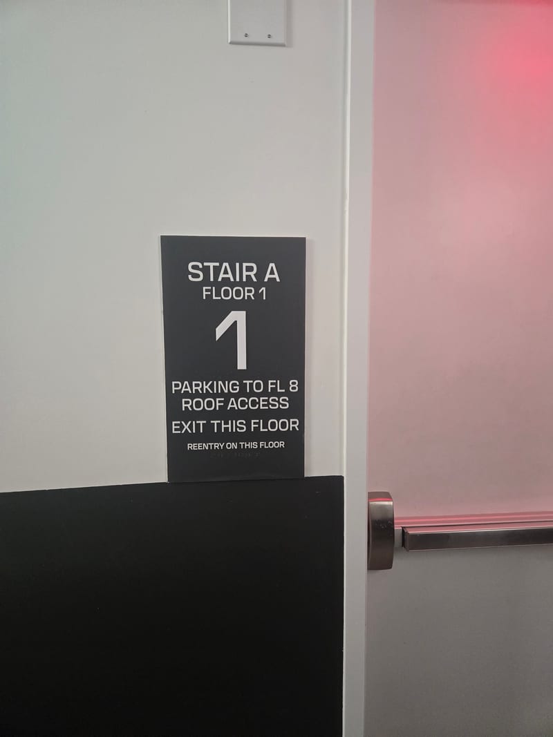 Stair ID sign beside a stair door with an emergency light.